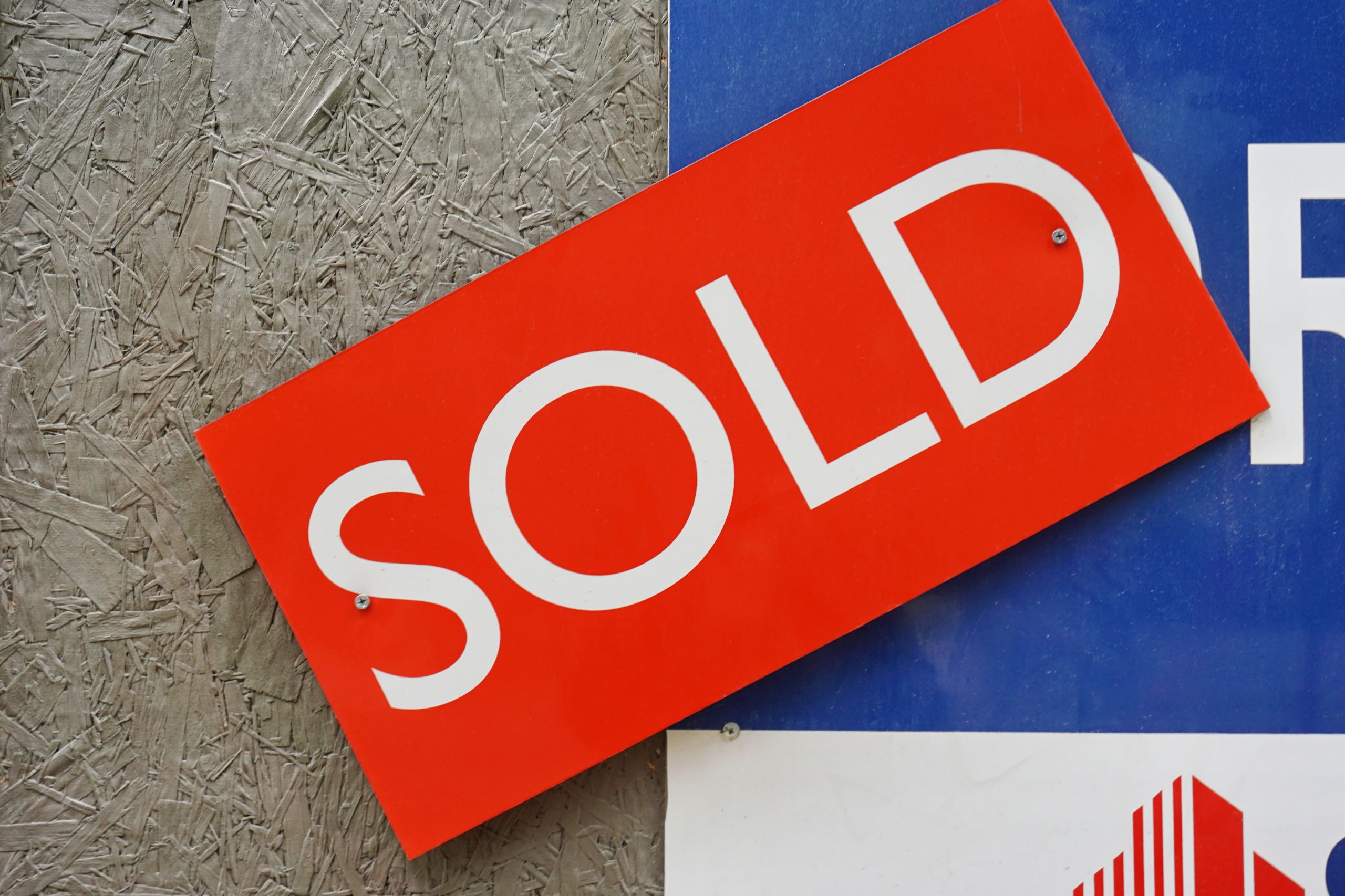 Red sold sign attached to a real estate sign