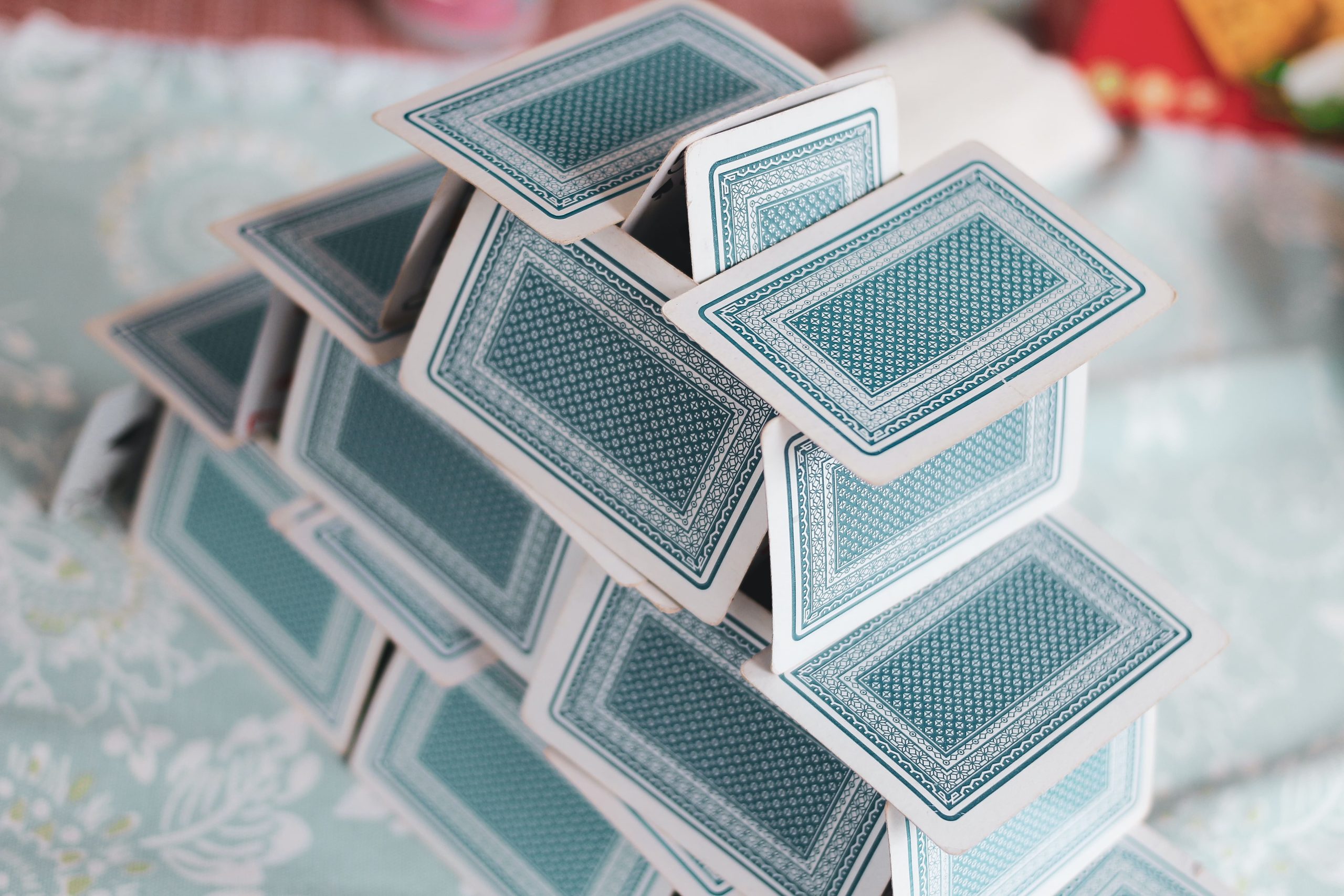 Photo of a house of cards. The cards are light blue.