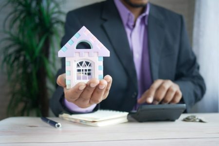 Man in a suit holding a toy house
