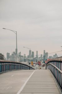 Melbourne city skyline in the background, cyclist bridge in the foreground.