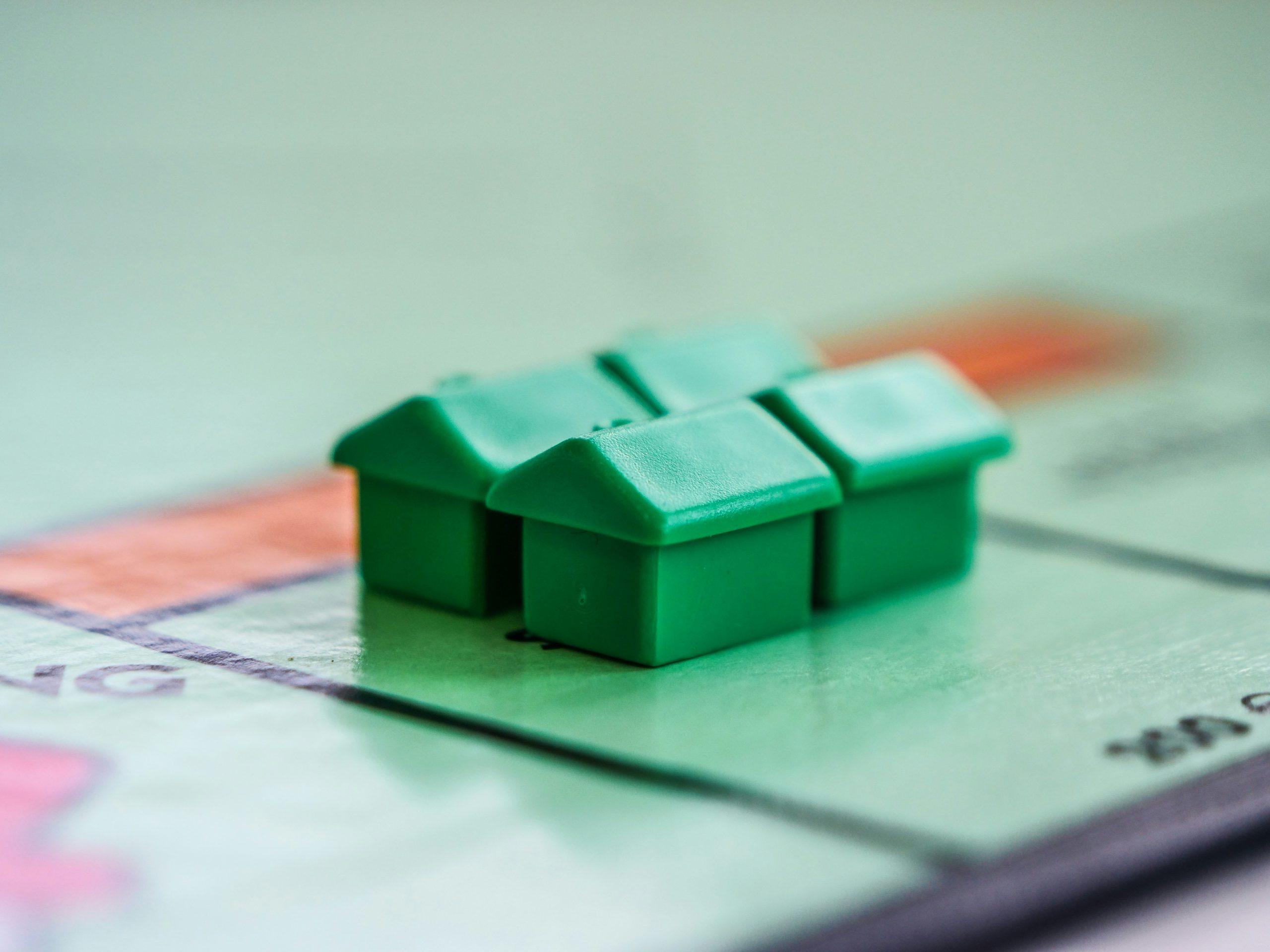 Green plastic houses on a monopoly board