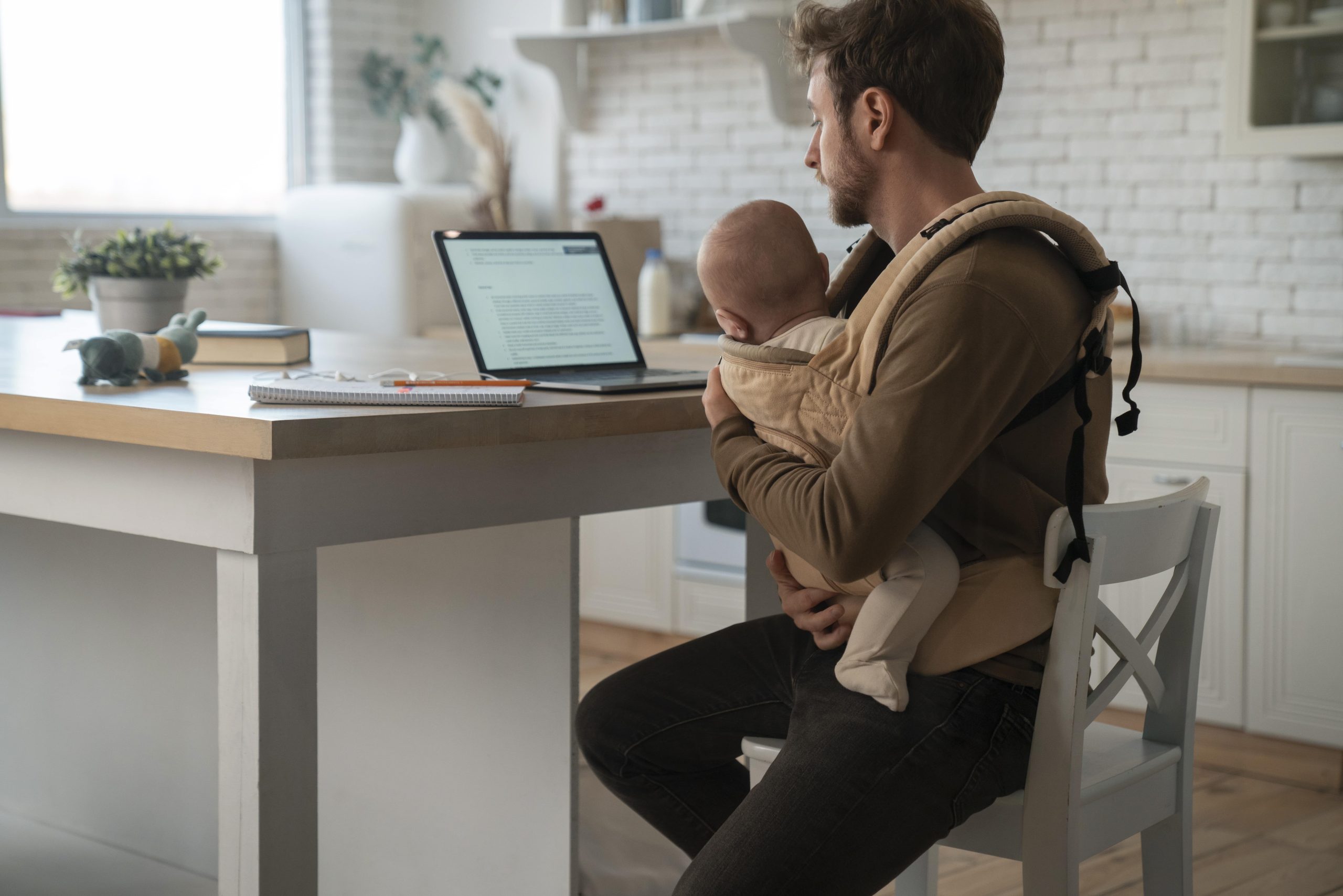 Father holding a baby while working
