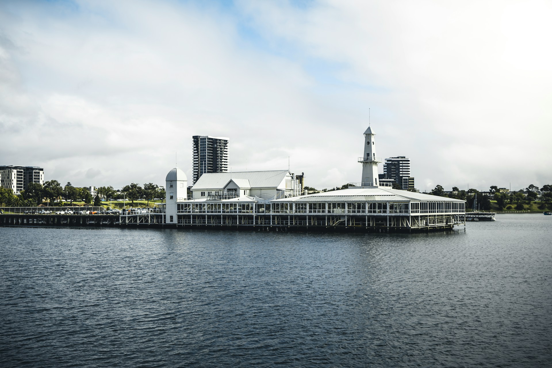 View of the Geelong waterfront and CBD from the sea. A large building is in the foreground overlooking the water. Tall buildings are visible in the background.